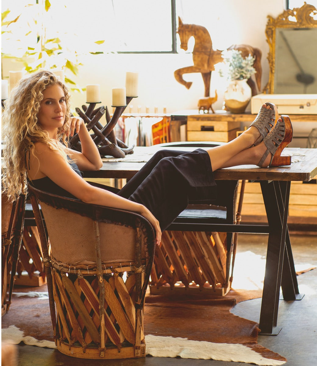 A woman sitting on a Fontella chair in a living room by Bed Stu.