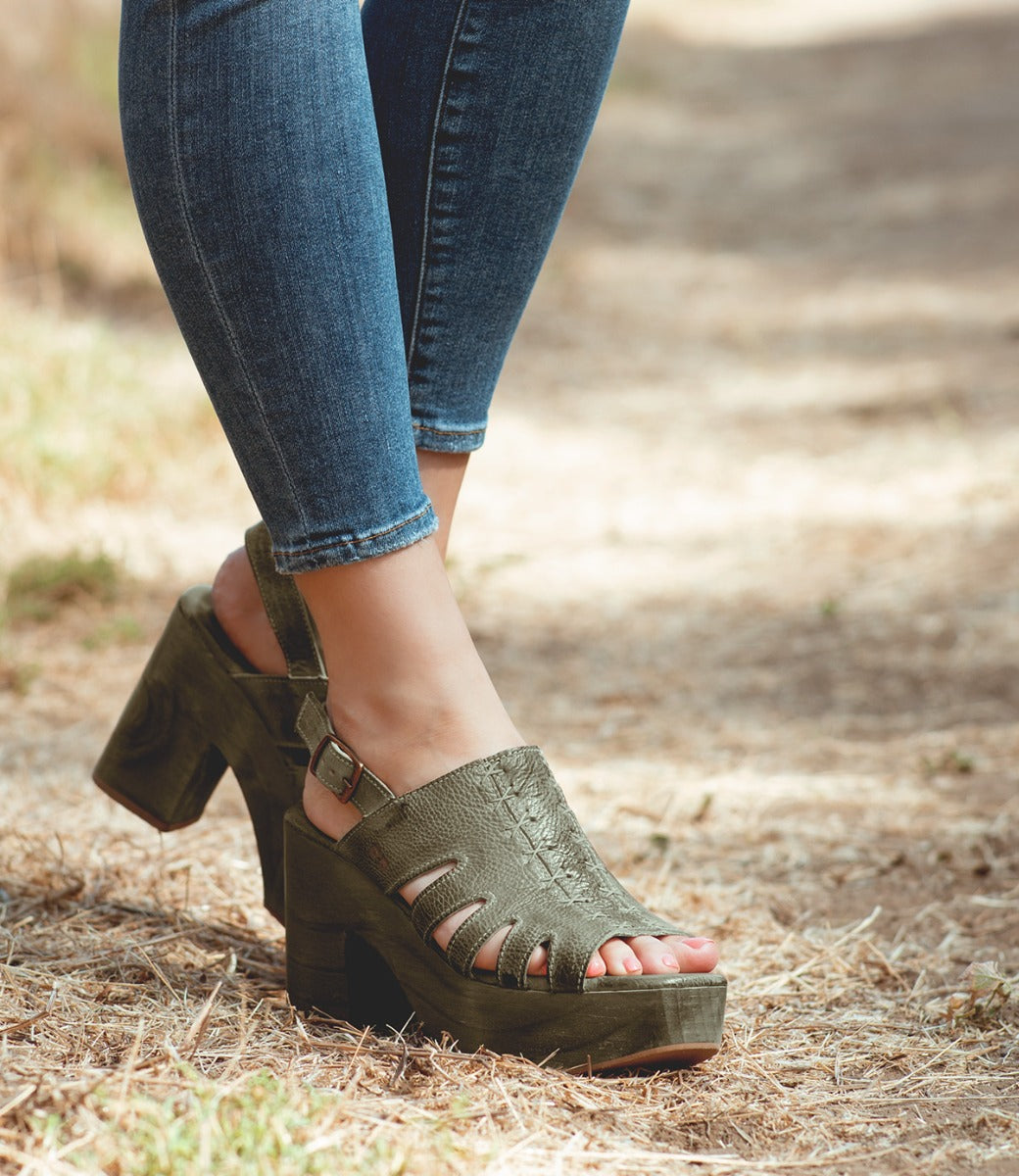 A woman in Bed Stu's green Fontella sandals standing on grass.