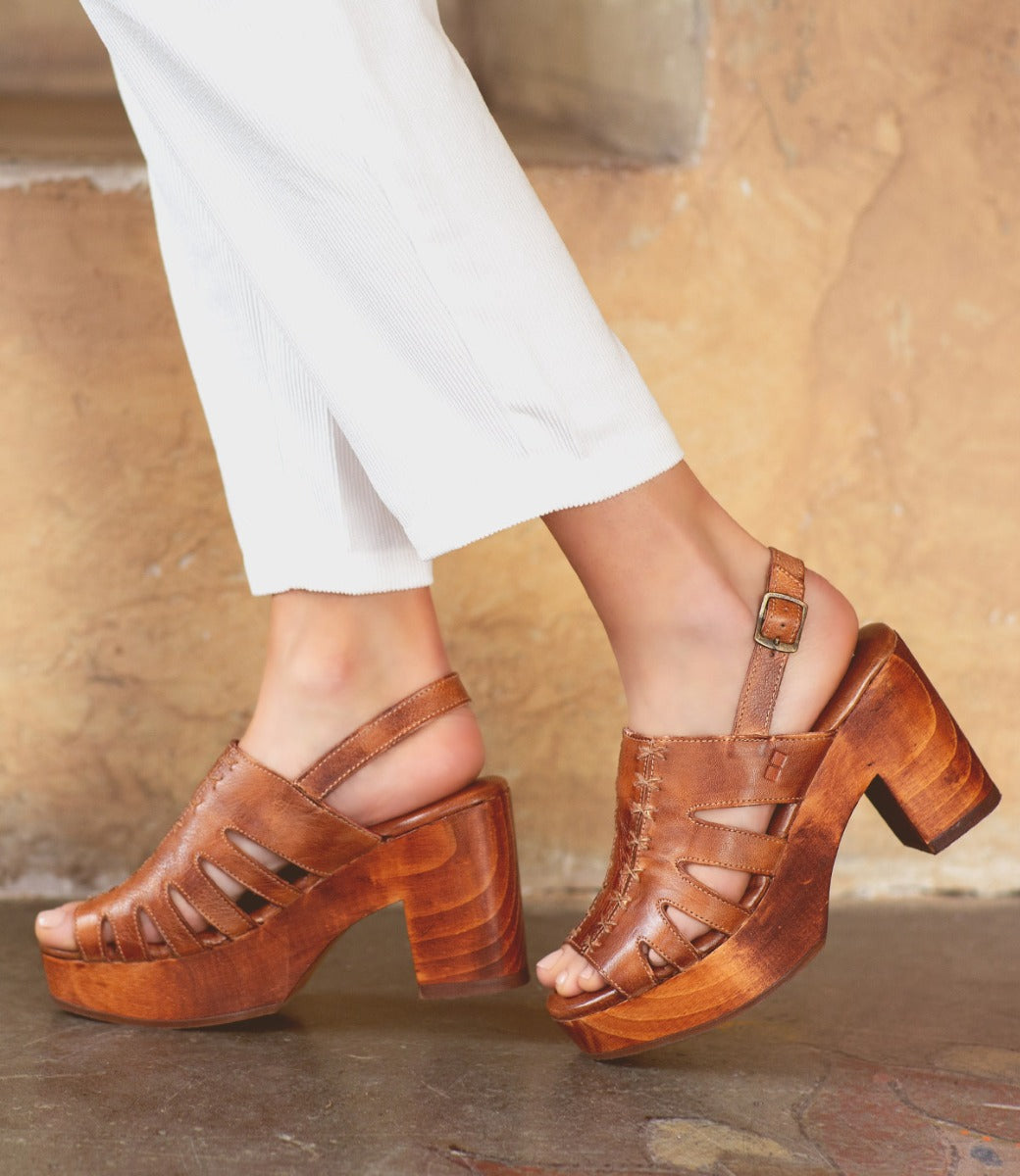 A woman wearing white pants and a pair of Bed Stu Fontella wooden sandals.