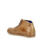 The Bed Stu "Formation" is a tan leather high-top sneaker with dark laces and a contrast sole, shown side-on against a white background, highlighting subtle leather details that enhance its vulcanized style.
