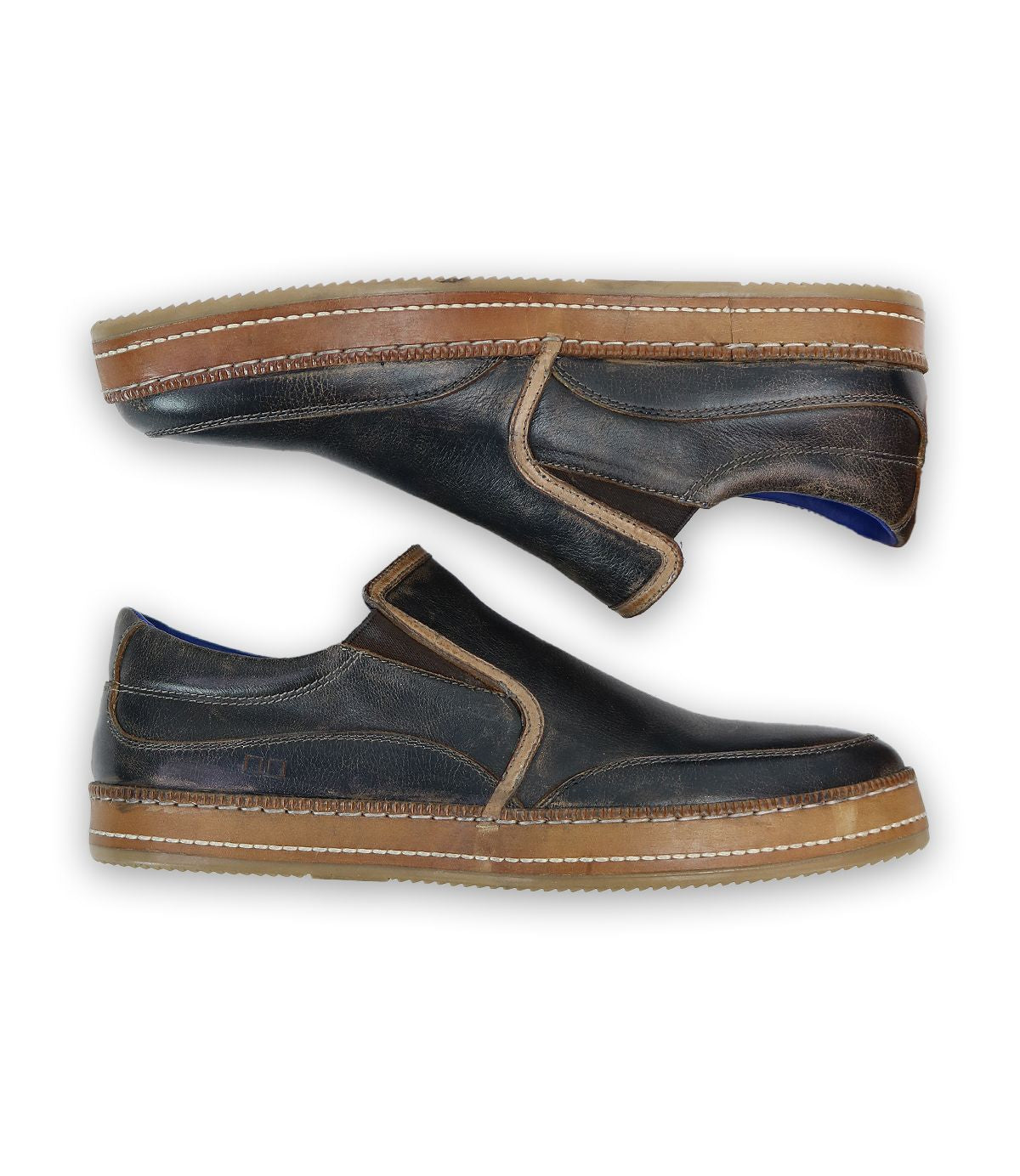 The Bed Stu Freestyle pair of dark brown slip-on shoes with tan stitching and brown soles, shown from a side view against a white background, exudes casual sophistication with intricate leather detailing.