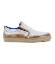 The Bed Stu Freestyle is a casual slip-on sneaker with a light beige fabric upper, leather detailing, and a tan rubber sole.
