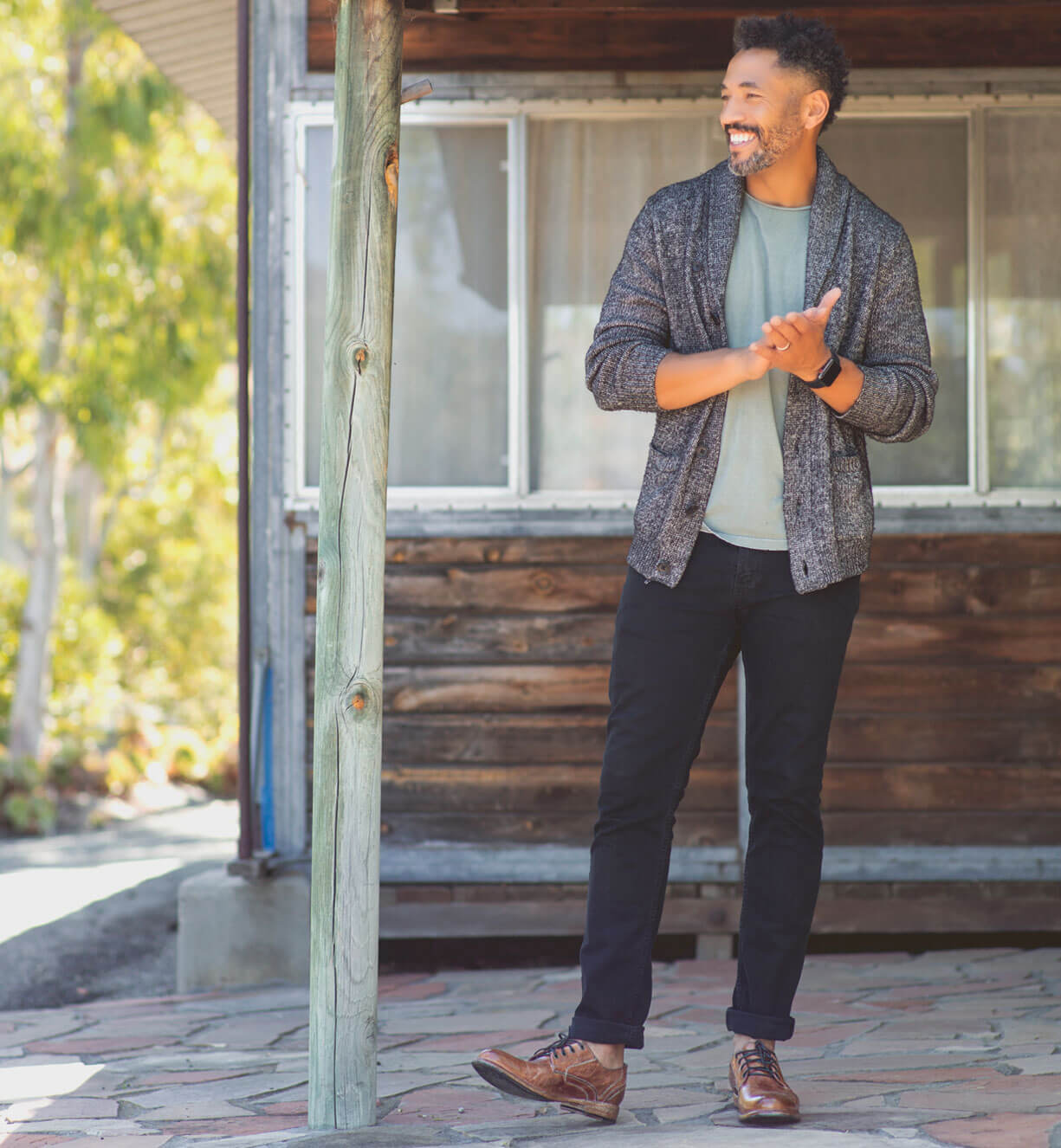A man standing in front of a house holding a Bed Stu Galao.