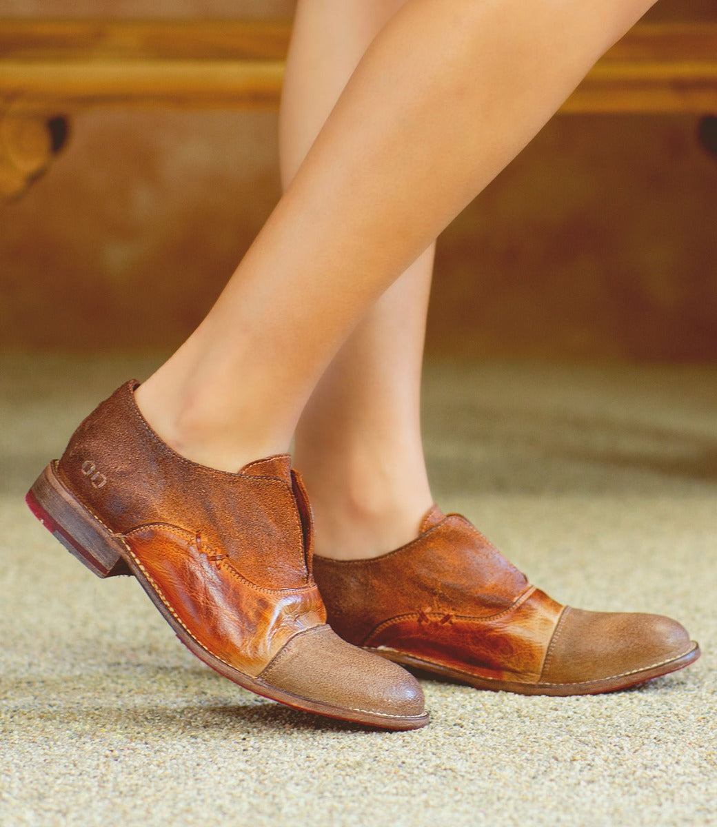 A woman wearing a pair of Bed Stu Garden M brown shoes on a bench.