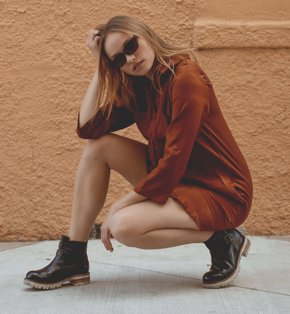 A woman is crouching down in front of a wall, wearing the Ginger boots by Bed Stu.