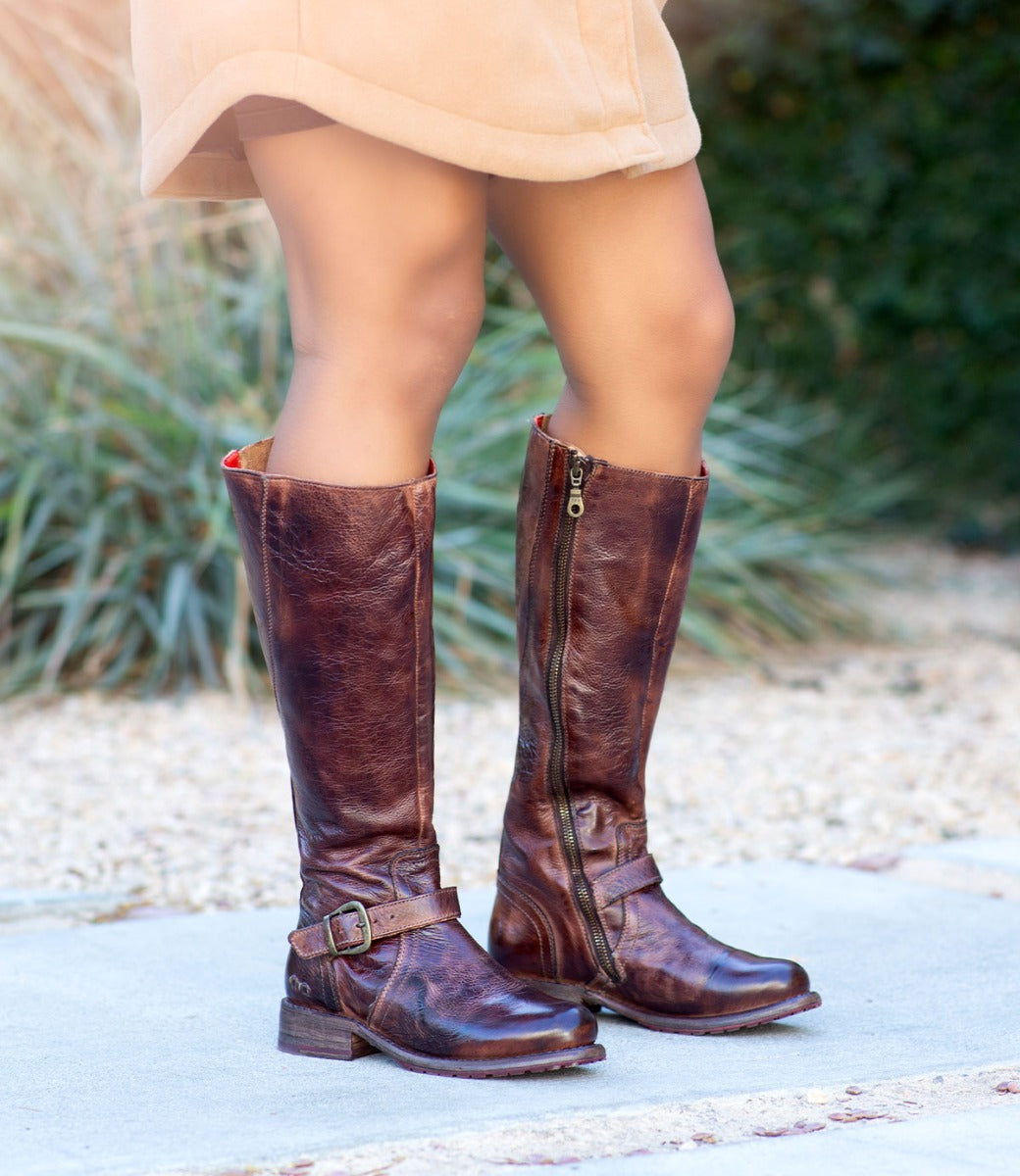 A woman wearing Bed Stu Glaye brown leather boots and a tan skirt.