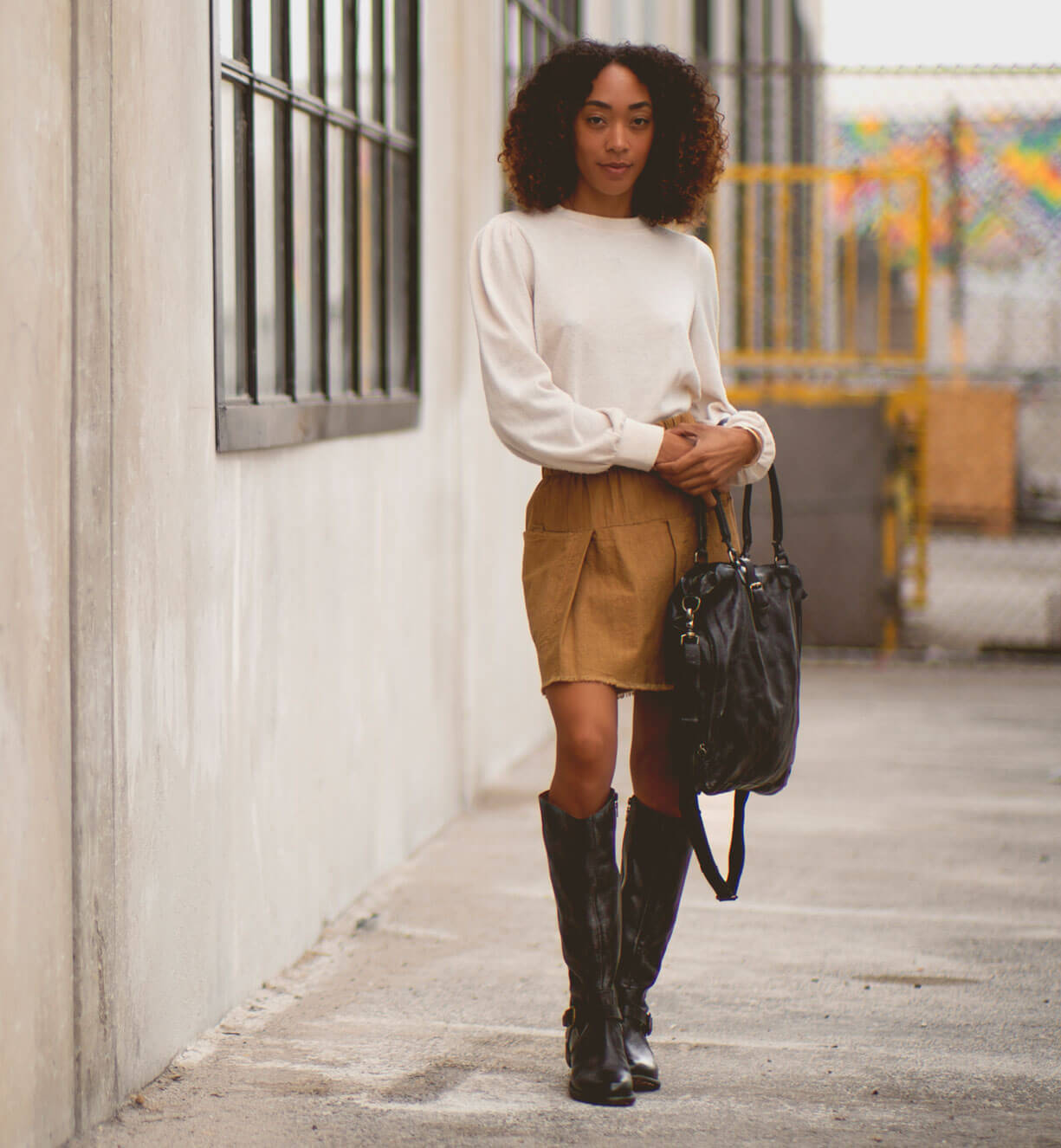 A woman in a tan sweater and Bed Stu knee high boots.