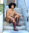 A woman wearing Glaye boots and a tan jacket sitting on steps. (Brand Name: Bed Stu)