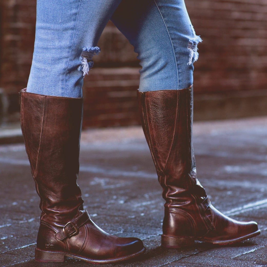 A woman in Glaye Wide Calf boots by Bed Stu standing on a brick street.
