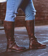 A woman in Glaye Wide Calf boots by Bed Stu standing on a brick street.