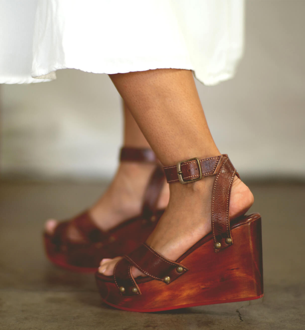 A woman's feet in a pair of Bed Stu Grettell brown wedge sandals.