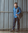 A man standing in front of a wall holding a Bed Stu Hampton II bag.