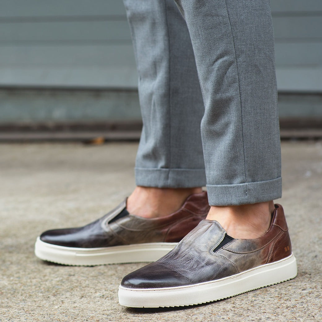 A man wearing grey pants and a pair of Bed Stu Harry slip-on shoes.