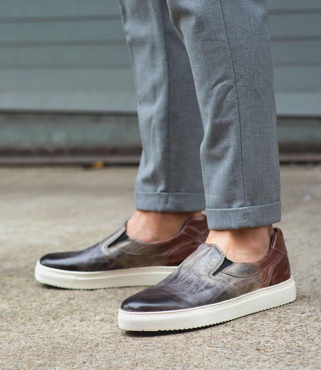 A man wearing grey pants and a pair of Bed Stu Harry slip-on shoes.