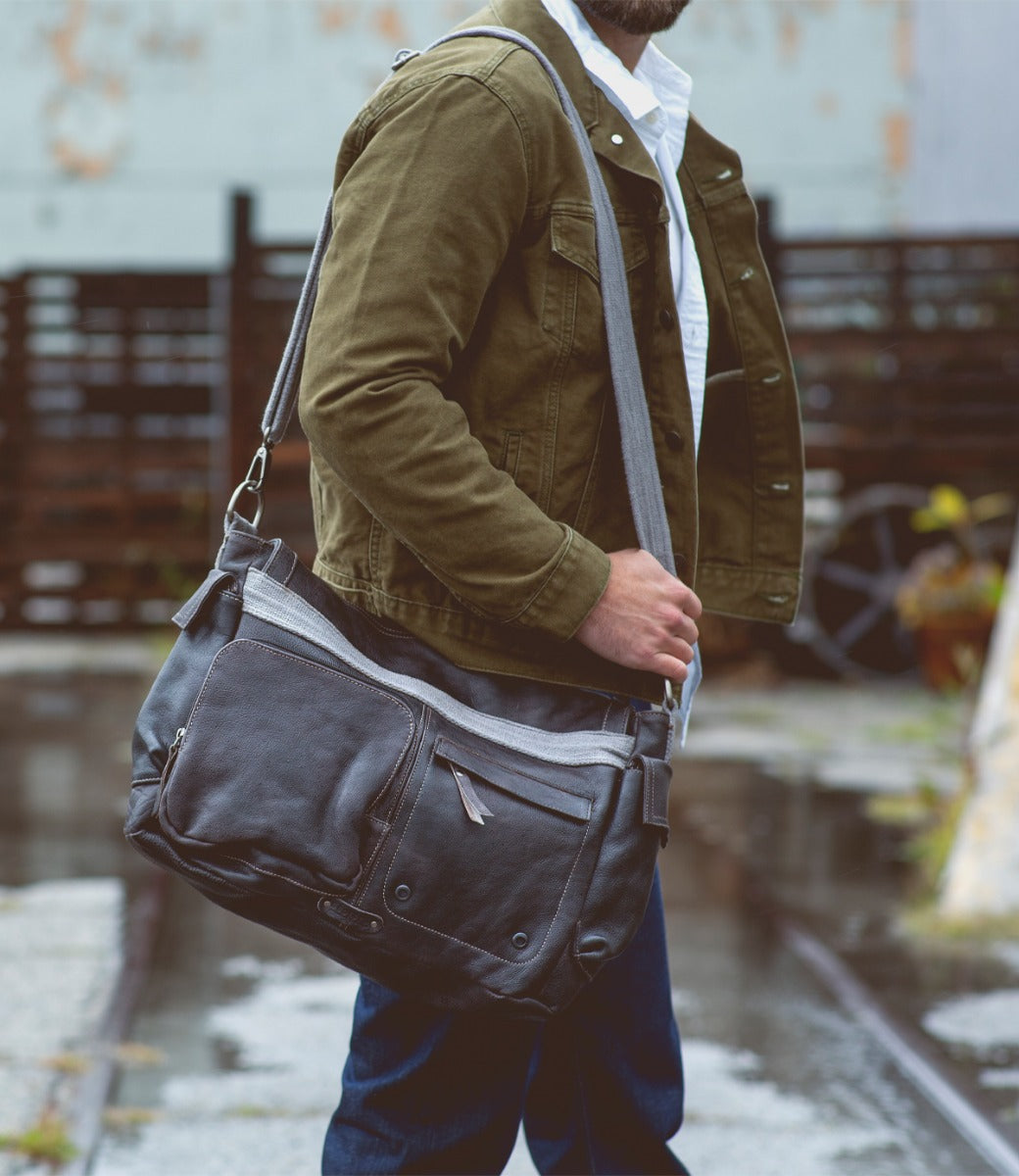 A man carrying a Bed Stu Hawkeye II messenger bag on a street.