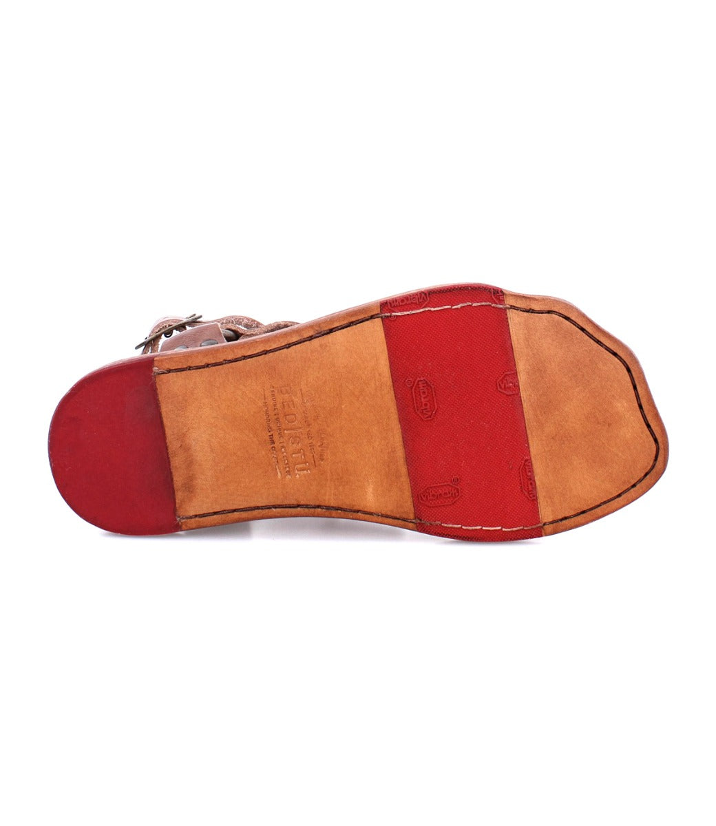 A pair of Hera shoes with a red and brown sole by Bed Stu.