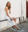 A woman wearing a white dress and Bed Stu Hermione sneakers.
