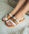 A woman in a pair of white and brown Bed Stu Hilda sandals.