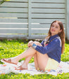 A woman sitting on the grass in tan Holland sandals by Bed Stu.