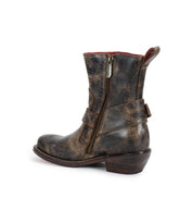 The Bed|Stü “Homage” is a distressed brown leather ankle boot featuring a square toe, side zipper, pull tab, and low stacked heel, shown in profile against a white background.