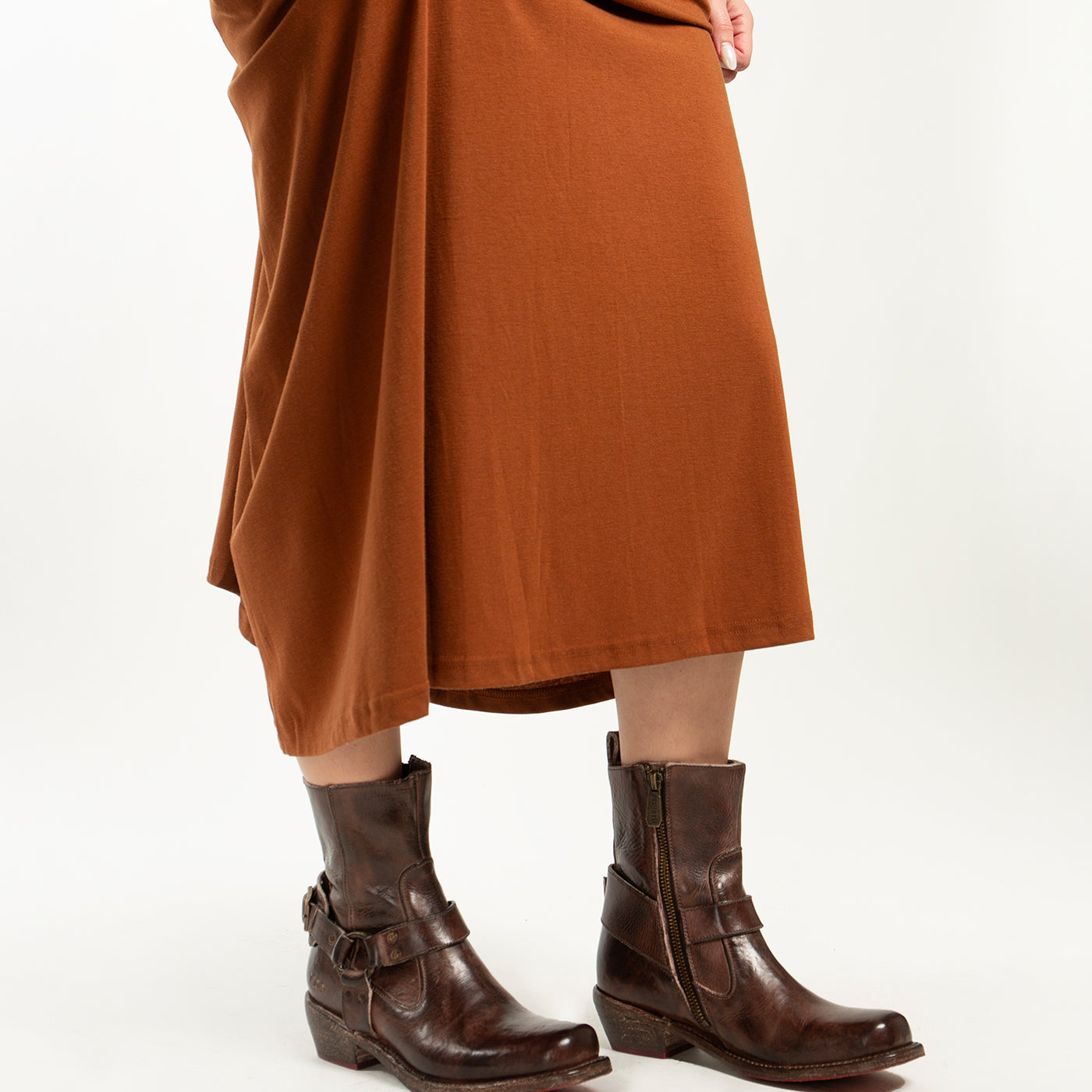 A person wearing the Homage rust-colored midi dress paired with Bed Stu dark brown square toe boots with buckles, standing against a plain white background.