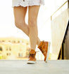 A woman in a white skirt and tan Bed Stu sneakers.
