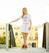 A blonde woman wearing a white t-shirt and Bed Stu skirt with the Honor brand.