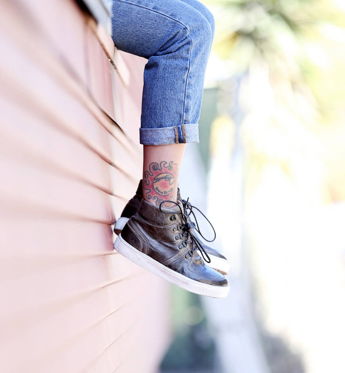 A person with Honor tattoos leaning against a wall. (Brand: Bed Stu)