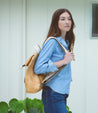 A woman wearing jeans and a tan Bed Stu Howie backpack.