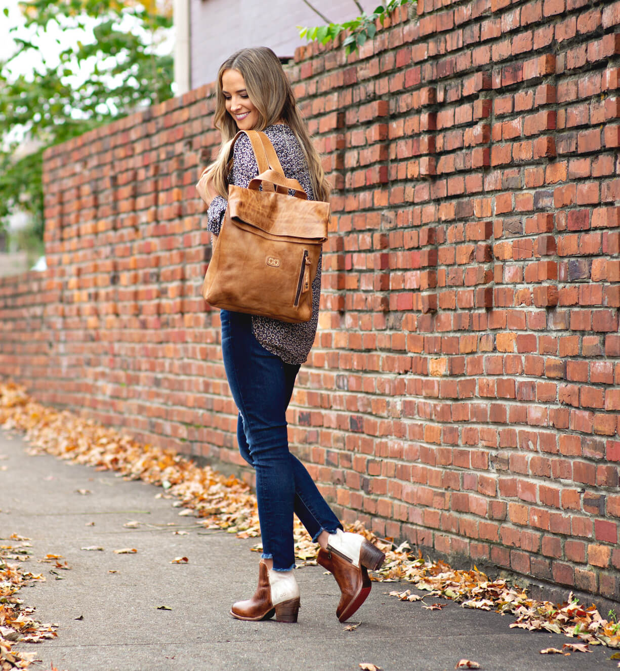 A woman wearing jeans and a Bed Stu Howie tan leather backpack.