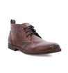 A brown vegetable-tanned leather Illiad chukka boot with blue laces, isolated on a white background by Bed Stu.