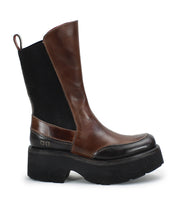 The Illicit boot by Bed Stu features a brown and black leather design, enhanced with a thick, chunky platform sole and a convenient pull tab on the back, delivering a nostalgic fashion vibe with retro flair.