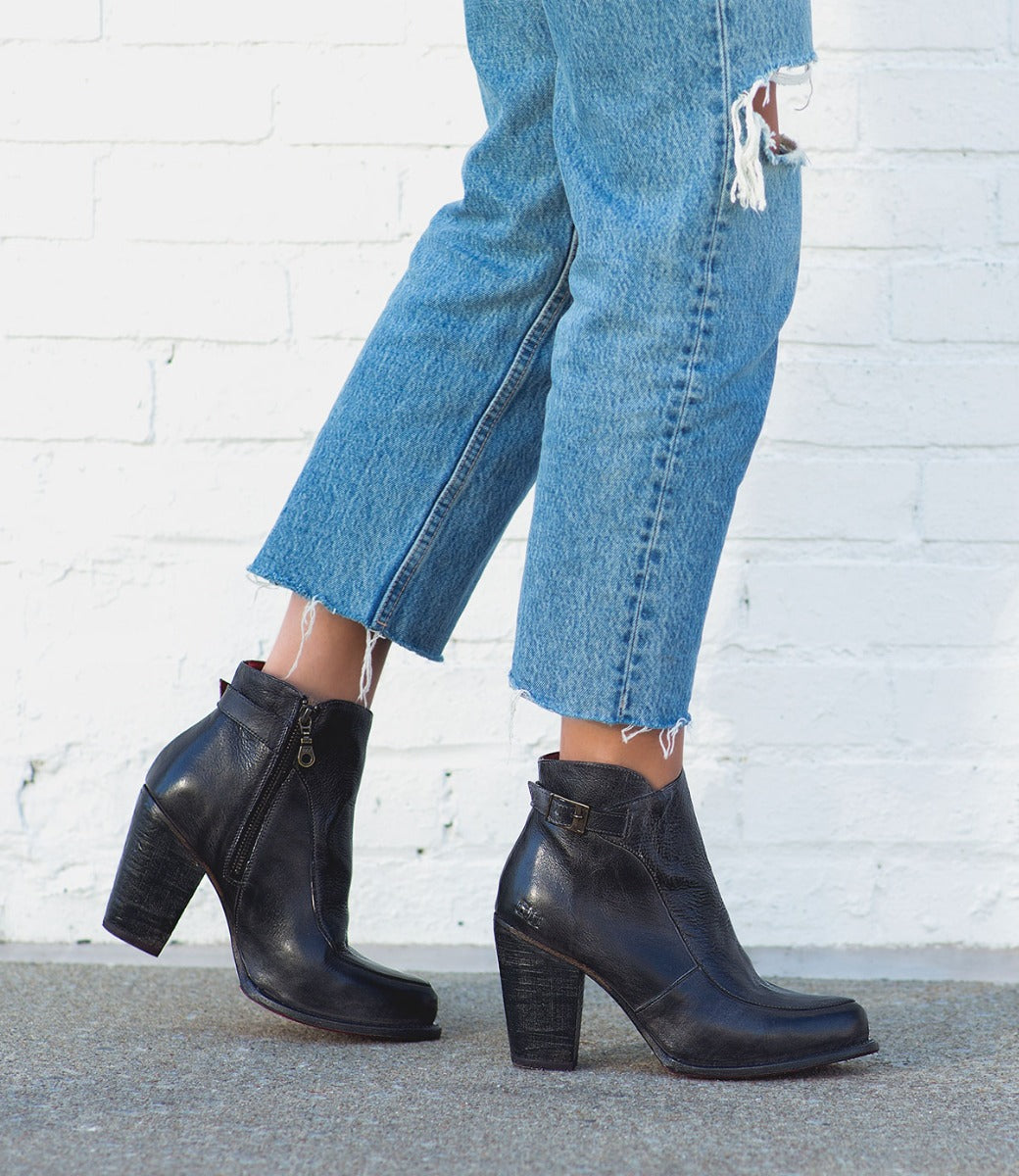 A woman wearing jeans and black Bed Stu Isla ankle boots.