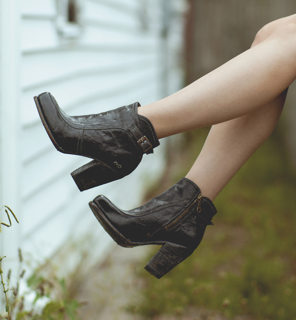 A woman's Isla legs are hanging off the side of a house wearing Bed Stu Isla.