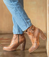 A woman's legs are leaning against a wall in a pair of Bed Stu Isla boots.
