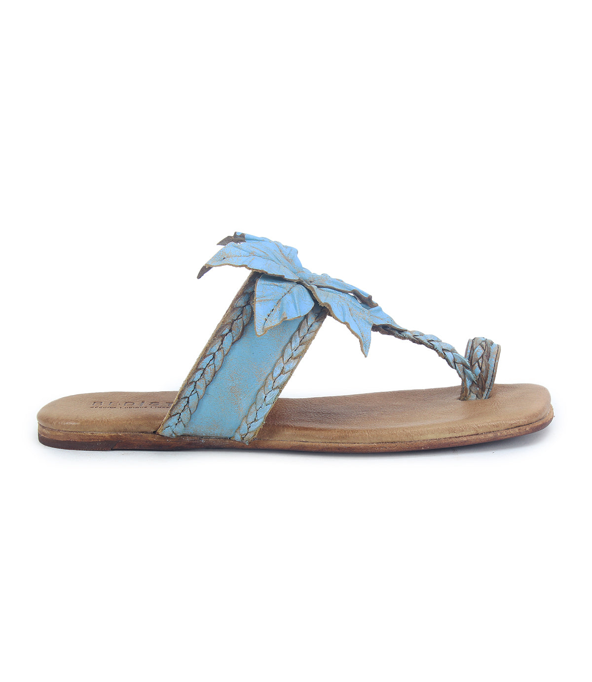 The Bed Stu Isobel is a flat sandal with a tan sole, light blue braided leather straps, a leather flower-shaped leaf accent on top, and a small toe loop.