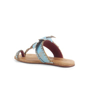 The Bed Stu Isobel is a flat sandal featuring a tan sole and two light blue braided leather straps—one over the toe and one across the top of the foot—shown on a white background.