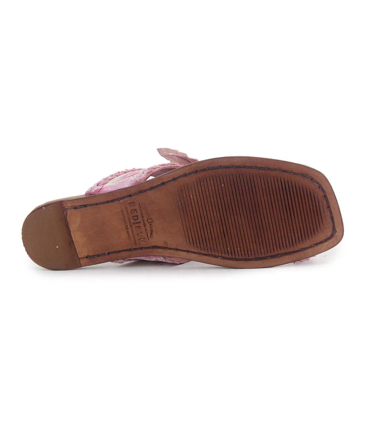 The image features the underside of a single brown sandal named Isobel by Bed Stu. It has a textured grip, visible stitching, braided leather details, and a leather flower on the strap. The brand name is imprinted near the heel.