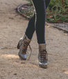 A woman walking down a path in a pair of Bed Stu Izetta boots.