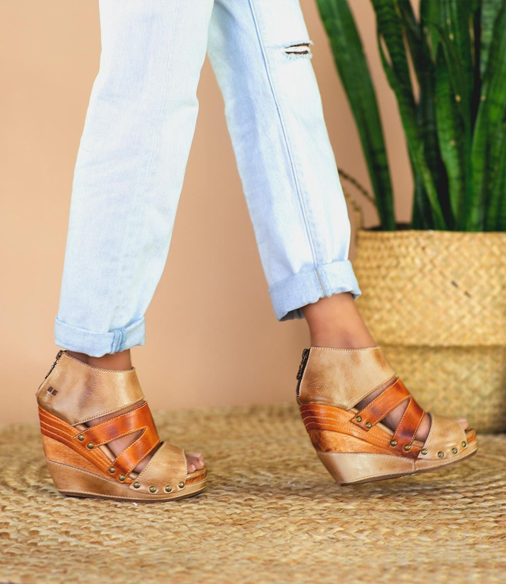 A woman wearing jeans and tan Bed Stu Jacey II wedge sandals.
