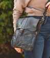 A woman is holding a black leather Jack cross body bag from Bed Stu.