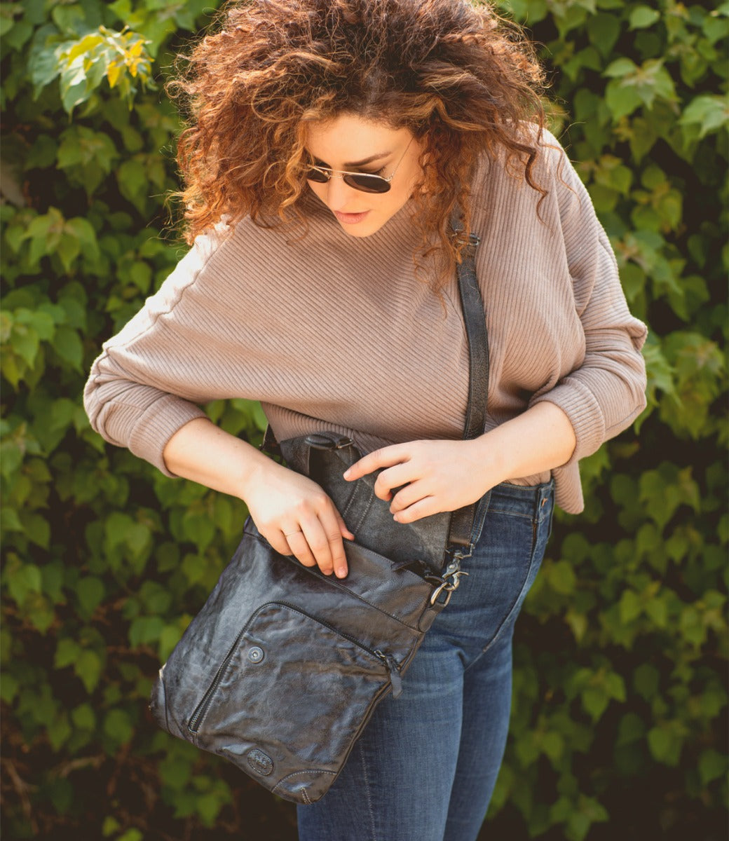 A woman with curly hair holding a Jack bag from Bed Stu.