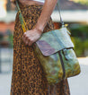 A woman wearing a leopard skirt and carrying a Bed Stu Jack green leather bag.