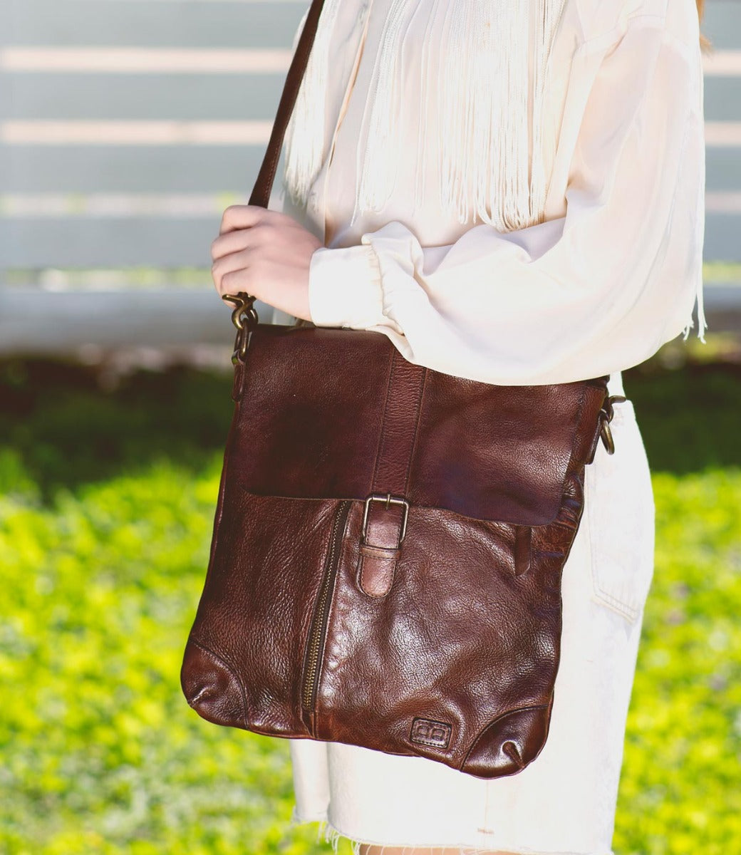 A woman holding a brown leather Bed Stu Jack crossbody bag.