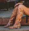 A woman is sitting on a wooden bench wearing Bed Stu Jacqueline boots.