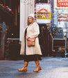 A woman walking down the street in a beige Jacqueline Wide Calf coat and Bed Stu boots.
