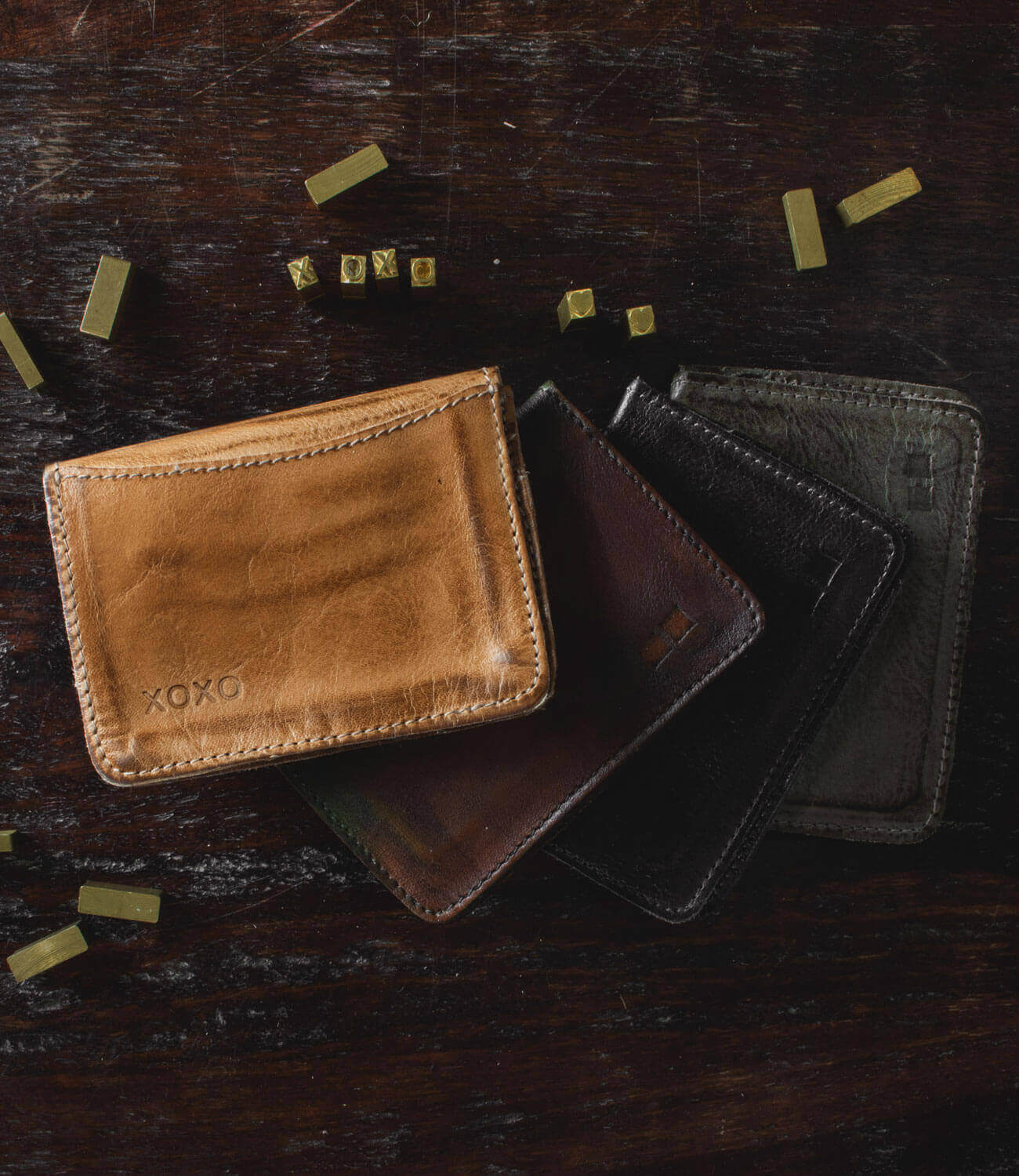 A group of Bed Stu Jeor leather wallets laying on top of a wooden table.