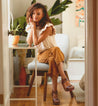 A woman sitting on a Jessie chair in a room.