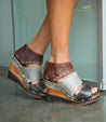 A woman's feet in a pair of Bed Stu Jessie wedge sandals.