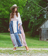 A woman wearing a dress and Jones sandals from Bed Stu, in front of a barn. 